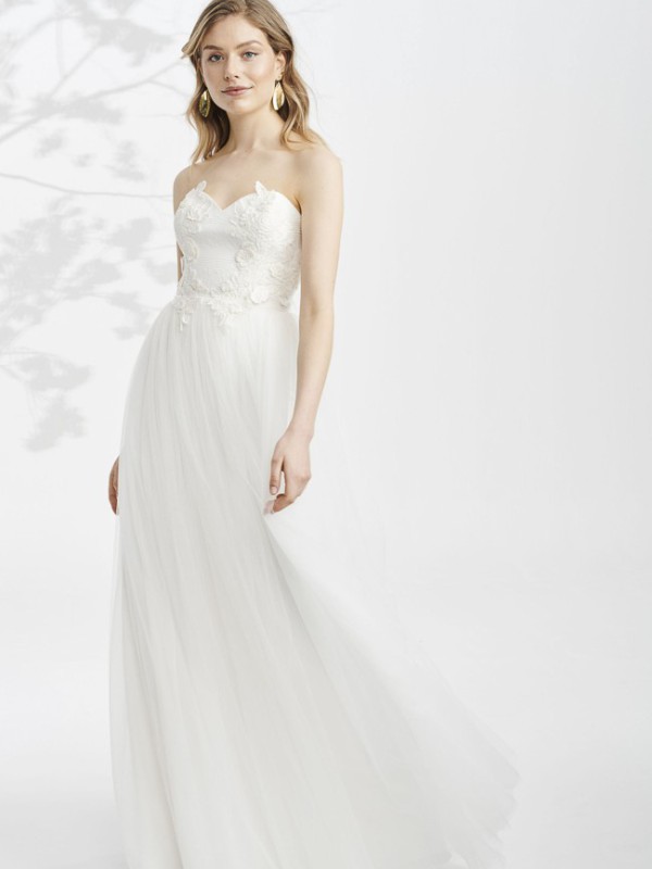 Klassisches trägerloses Brautkleid mit floralen Applikationen am Oberteil und fließendem Tüllrock im Studio