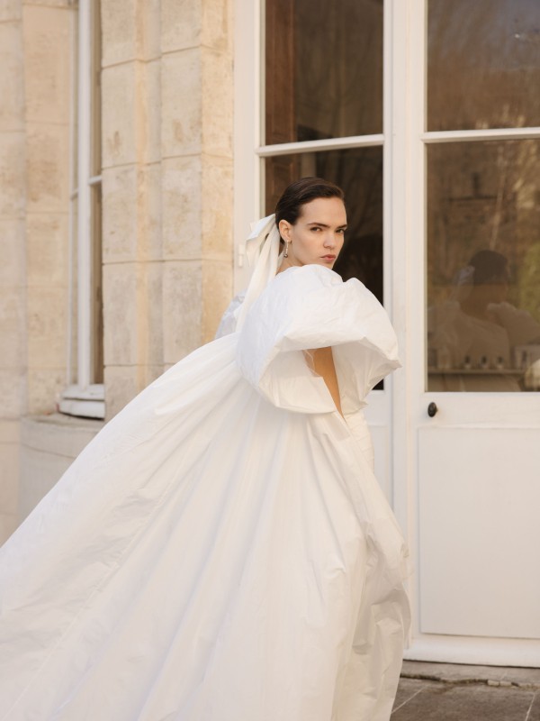 Voluminöses Brautkleid mit großer Schleppe und Puffärmeln, getragen vor einem historischen Gebäude