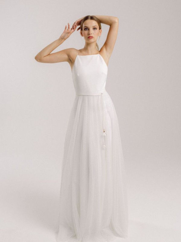 Clean-Brautkleid mit Halterneck, glattem Oberteil und leichtem Tüllrock, schlichtes und modernes Design, Braut mit blondem Haar vor hellem Studiohintergrund