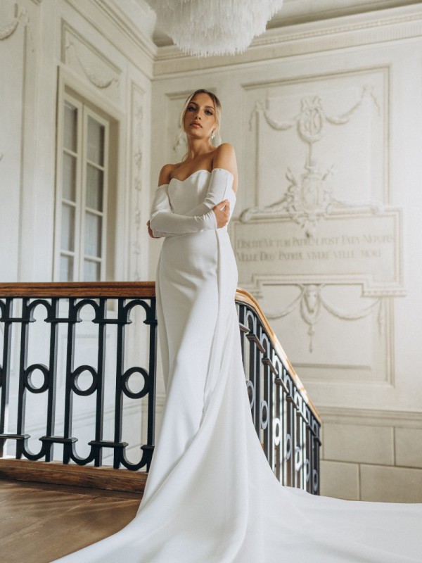 Klassisches Brautkleid schulterfrei mit langen Handschuhärmeln und eleganter Schleppe auf einer historischen Treppe