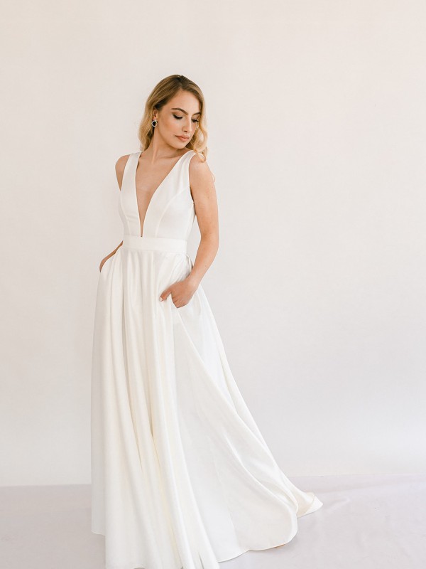 Klassisches Brautkleid mit tiefem V Ausschnitt betonter Taille und weitem Rock mit Taschen im Studio