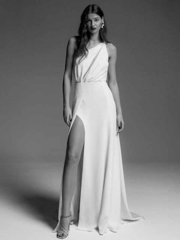 Eind schwarz-weiß Foto eines Models in einem leichten One Shoulder Brautkleid aus Seide mit Beinschlitz.