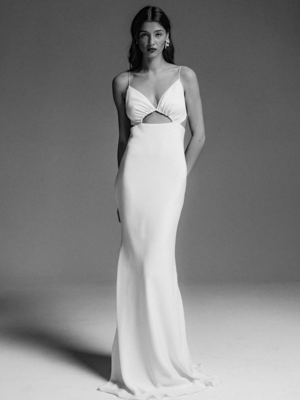 Clean-Brautkleid mit Cut-Out und schmalen Spaghettiträgern, glatter Stoff und minimalistische Silhouette, Braut mit langem dunklem Haar im Schwarzweiß-Look vor neutralem Hintergrund