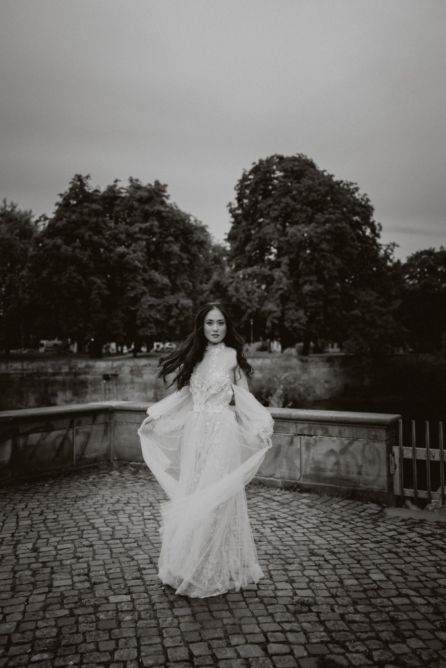 Stimmungsvolle Hochzeitsfotografie – Real Bride Iru trägt ein individuell angefertigtes Brautkleid mit fließendem Stoff. Schwarz-Weiß-Aufnahme in natürlicher Kulisse, aufgenommen von Diana Frohmüller