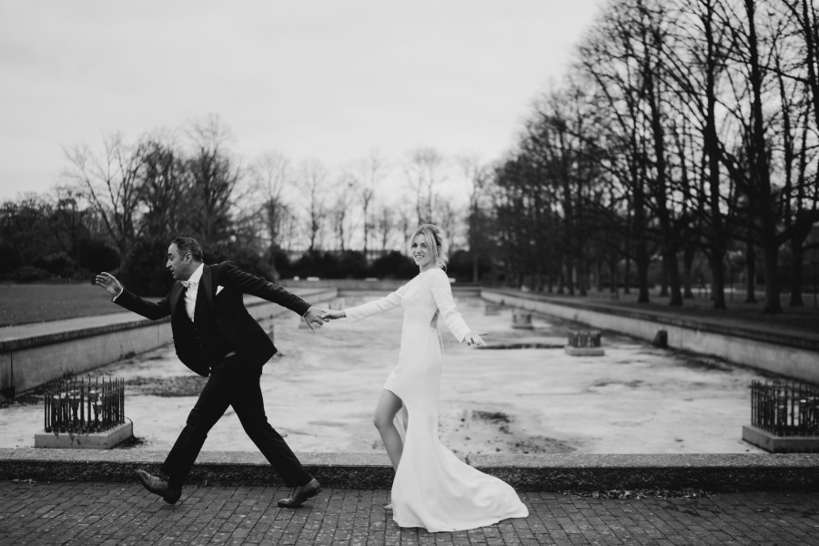 Braut und Bräutigam halten sich an den Händen auf einer baumgesäumten Allee – Cosmo Bride Moment.