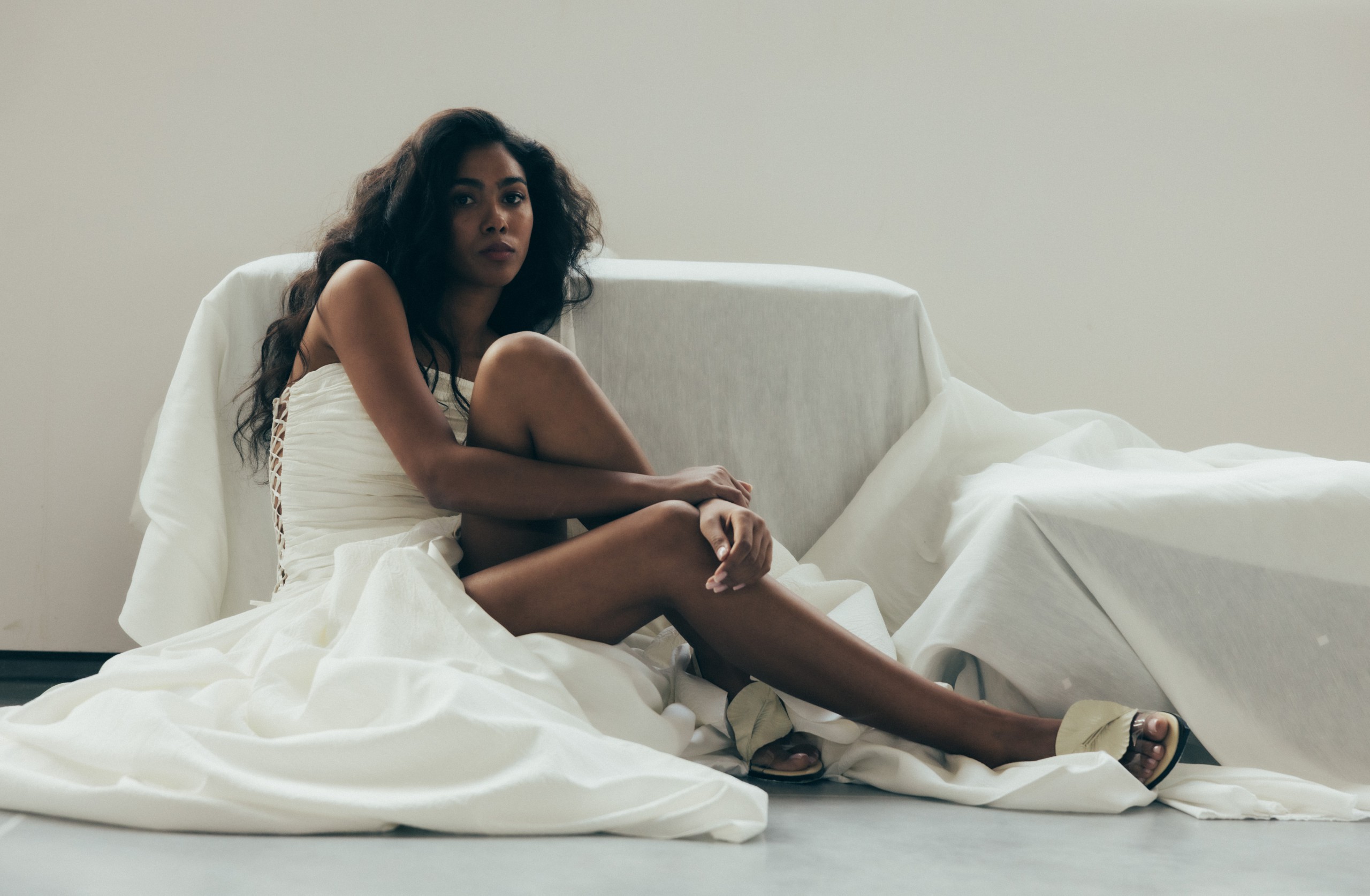 Eine Braut sitzend auf dem Boden in einem eleganten Designer Brautkleid aus Seide