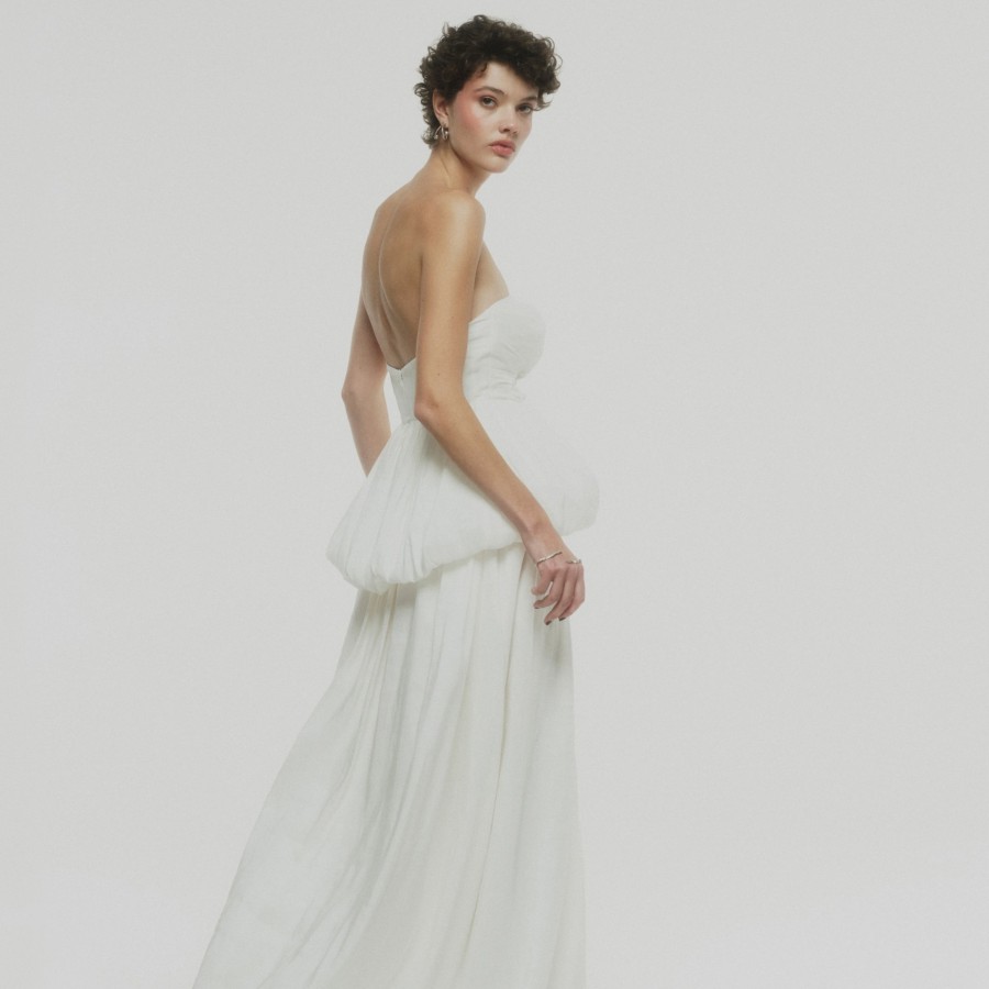 Braut in einem rückenfreien Brautkleid aus Seide posiert vor einem weißen Hintergrund.