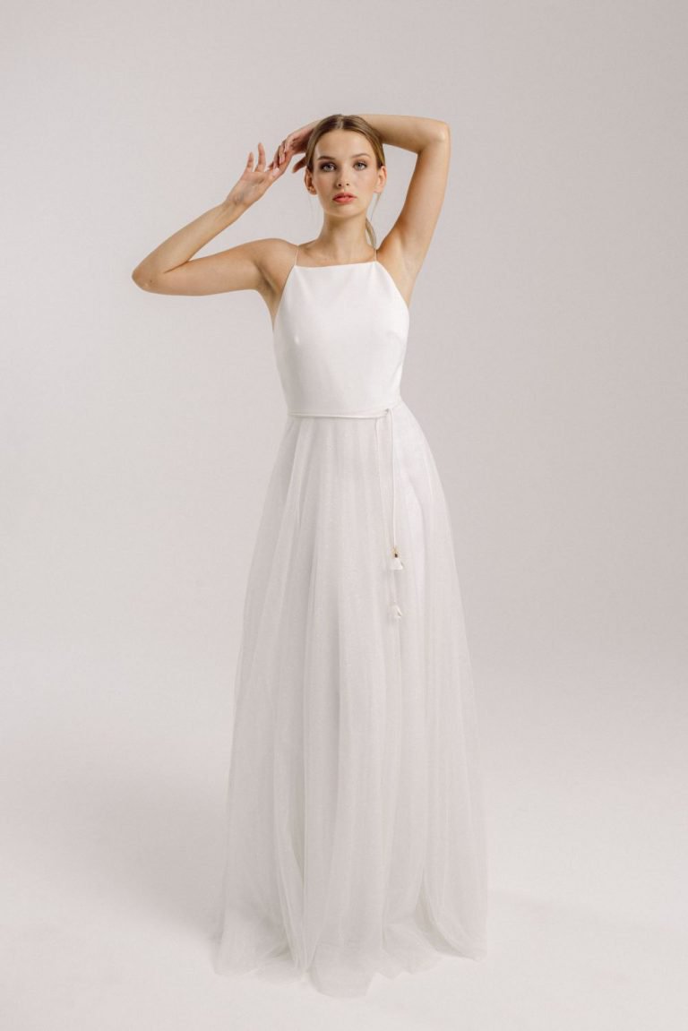 Eine junge Frau in einem boho vintage Brautkleid hebt die Arme hoch.