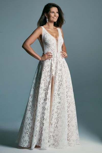 Ein Model trägt ein weißes langes Hochzeitskleid und posiert seitlich zur Kamera in einem Fotostudio.