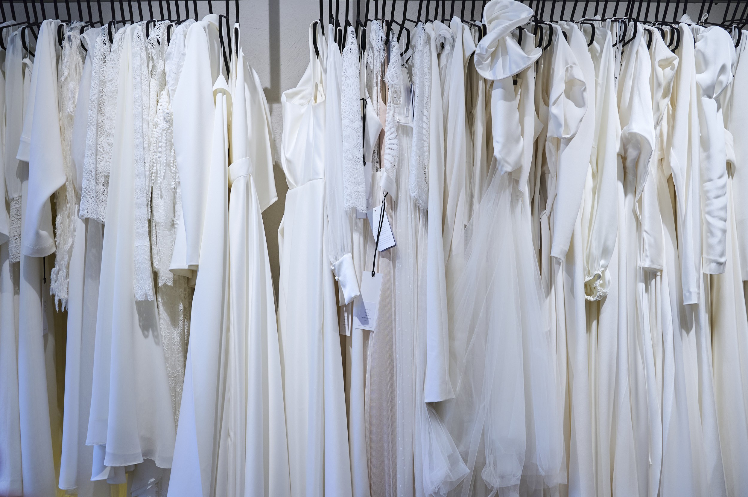 Brautkleider hängen hintereinander auf einer langen Stange im COSMOPOLKA Bridal Store in Hannover.