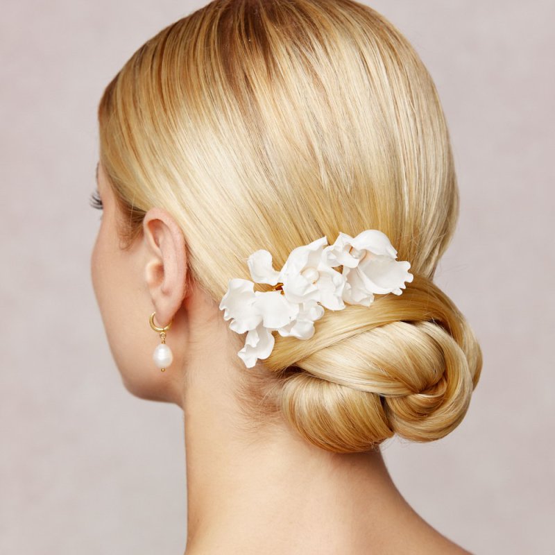 Brautfrisur mit Haarkamm 'Peony' in Gold, verziert mit Seidenblüten und Perlen, eingearbeitet in einen eleganten Knoten.