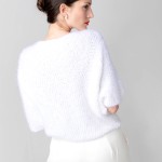 Rückansicht des handgestrickten weißen Braut-Pullovers mit lockerer Passform und kurzem Fledermausärmel. Der Pullover wird mit weiten, fließenden Hosen kombiniert, die dem Look Eleganz verleihen. thumbnail