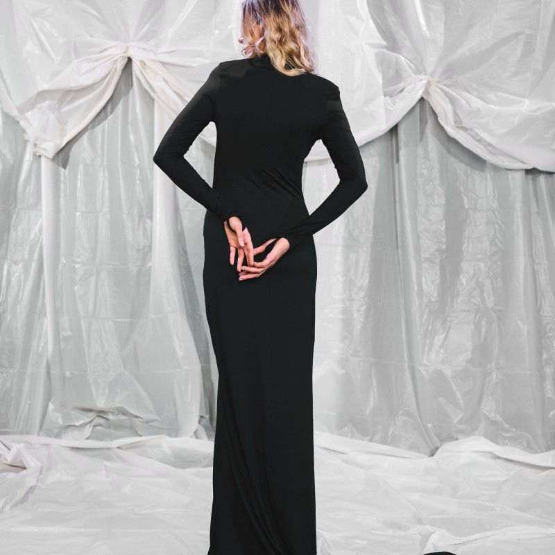 Rückansicht eines schwarzen Maxikleids mit langer, fließender Schleppe und figurbetontem Schnitt in Meerjungfrauenform. Elegantes Abendkleid, das die Silhouette stilvoll umschmeichelt.