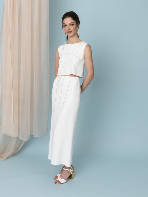 Eleganter Braut Zweiteiler mit hochgeschlossenem Cropped-Top und figurbetontem Bleistiftrock in Weiß. Dieser minimalistische Look kombiniert moderne und klassische Elemente, ideal für eine stilvolle Hochzeit.