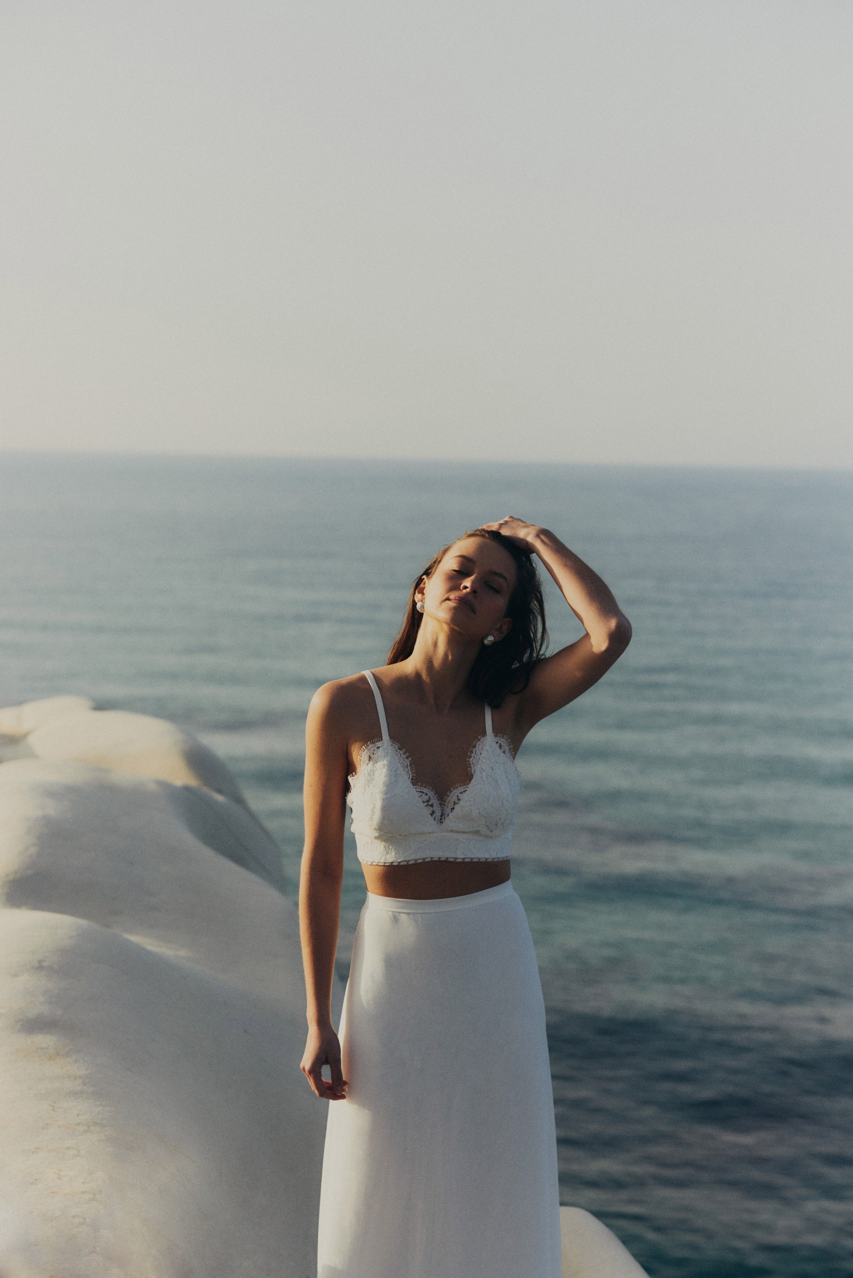 Zweiteiliges Brautoutfit mit zartem Spitzentop und fließendem, schmalem Rock – ein luftiger und romantischer Look für Hochzeiten am Meer.