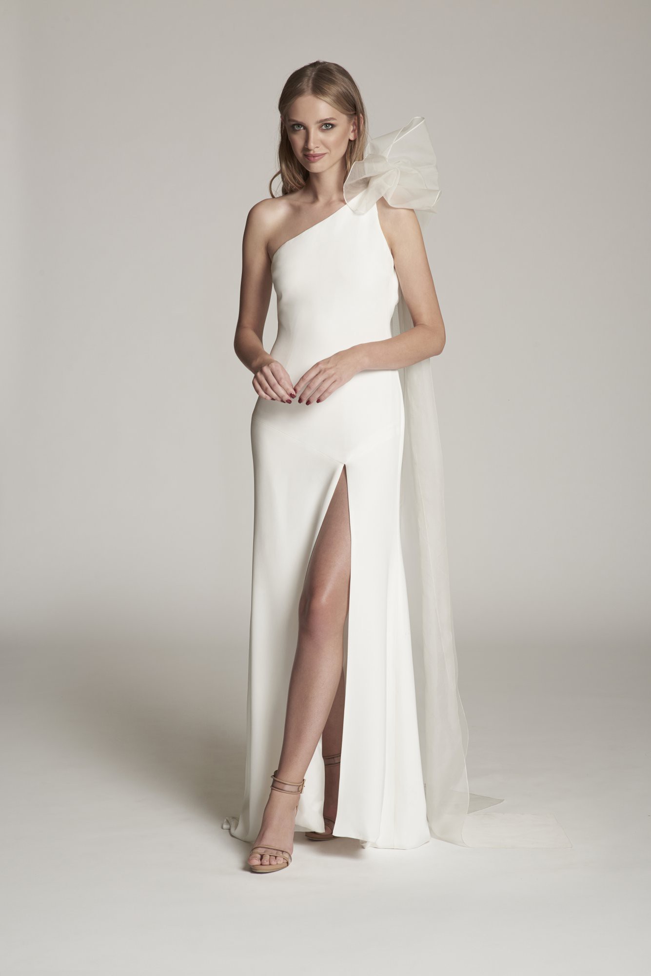 Elegantes One-Shoulder-Brautkleid mit hohem Beinschlitz und organzaartigem Schulterdetail – ein femininer und glamouröser Stil.