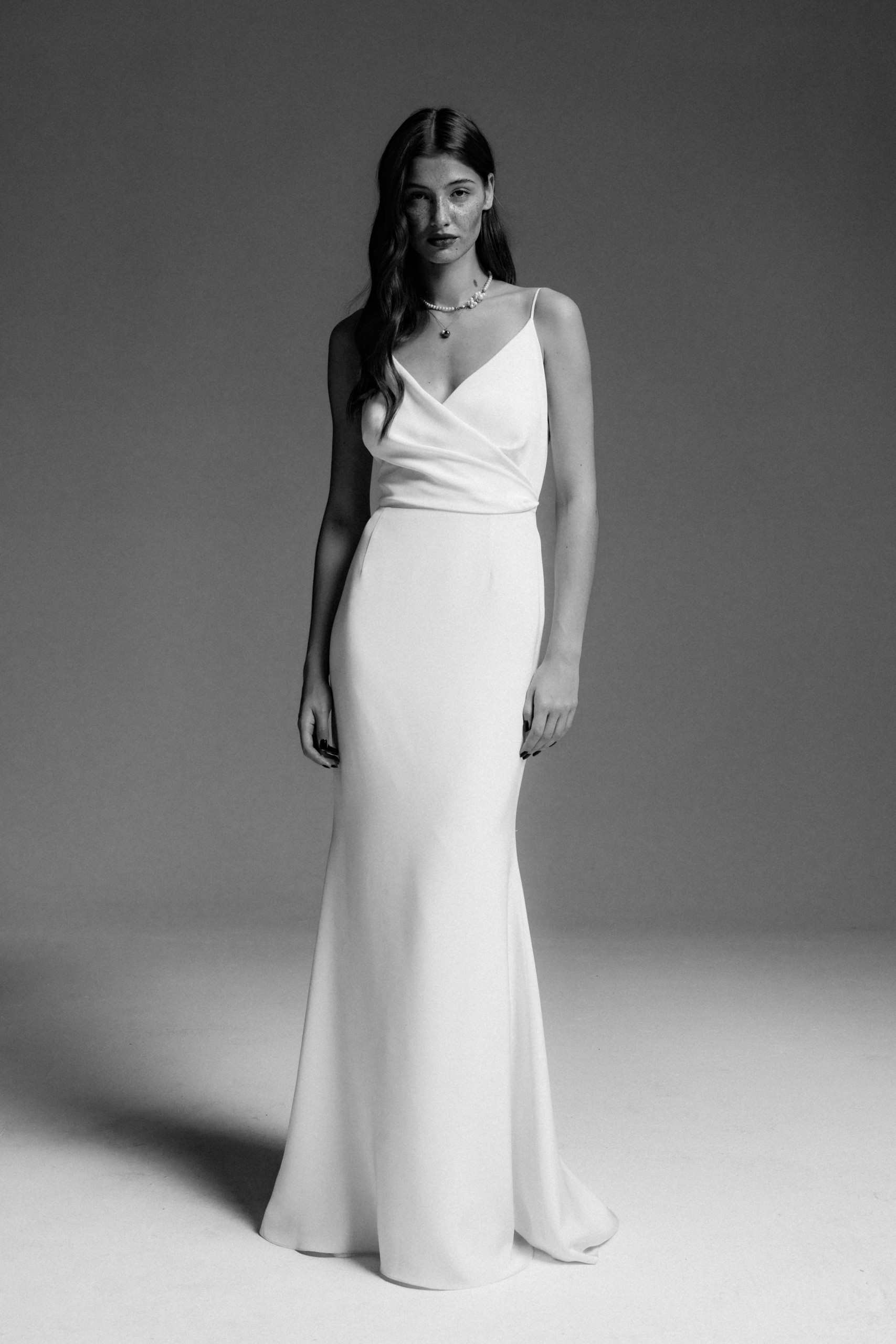 Minimalistisches Brautkleid mit V-Ausschnitt und schmaler Silhouette aus edlem Seidencrepe. Zeitloses und elegantes Design für moderne Bräute, die klare Linien und hochwertige Materialien schätzen.