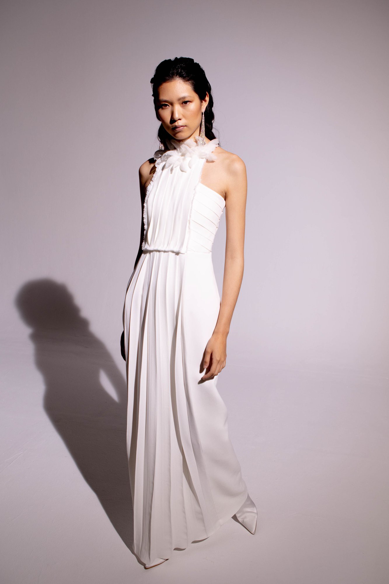 Neckholder-Brautkleid mit plissierten Details und floralen Applikationen am Hals – ein moderner und eleganter Look für besondere Anlässe.